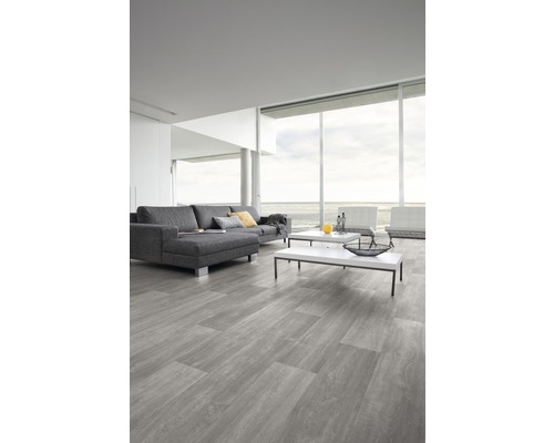 Séjour avec sol en vinyle gris imitation bois, canapé et tables basses.
