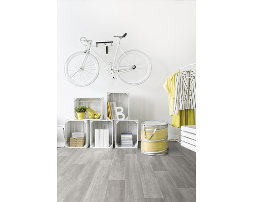 Pièce lumineuse avec un vélo blanc au mur, une étagère en caisses de bois et un revêtement de sol gris