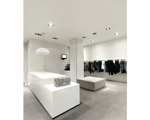 Innenaufnahme eines Bekleidungsgeschäfts mit Kasse, Kleidung und Beleuchtung