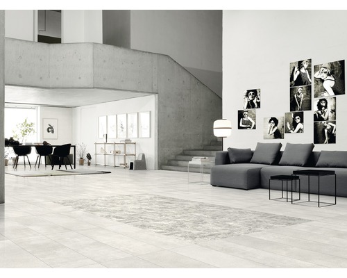 Espace de vie lumineux avec mur en béton, escalier, coin salon, table à manger et carrelage