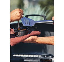 Szene mit Essen im Topf, Grillbesteck und Handtüchern vor einem Grill