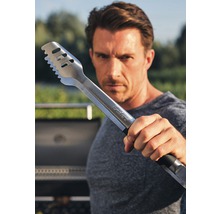 Mann hält Grillzange aus Edelstahl in die Kamera