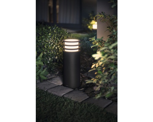 Base cylindrique éclairée d''un lampadaire de jardin le long d''une allée