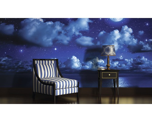 Séjour avec fauteuil, table de chevet et papier peint photo avec motif de nuit