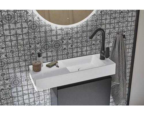 Vasque de salle de bains avec robinet, serviette et miroir devant un mur à motifs