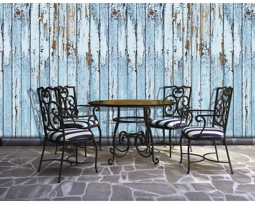 Scène avec table de jardin, quatre chaises et un mur avec de la peinture écaillée