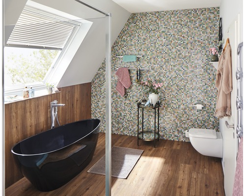 Salle de bains avec baignoire îlot, mur en mosaïque et fenêtre de toit