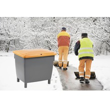 Conteneur à sel de déneigement avec personnel de service hivernal en arrière-plan