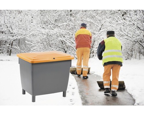 Conteneur à sel de déneigement avec personnel de service hivernal en arrière-plan