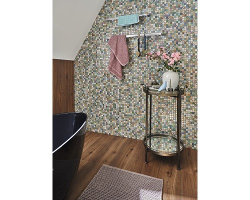 Salle de bains avec mur en mosaïque, baignoire, serviettes et table d''appoint