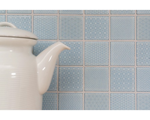 Dekorative quadratische Wandfliesen mit Mustern hinter einer Teekanne