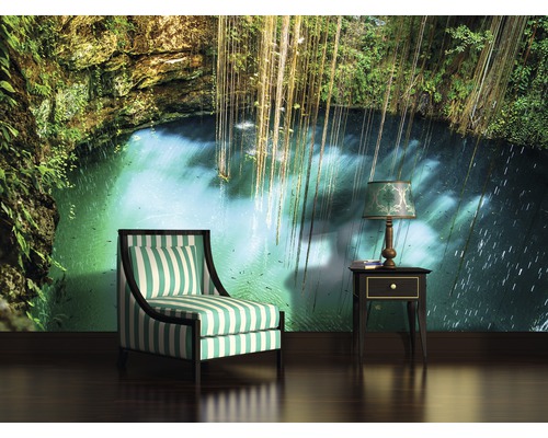 Papier peint avec motif jungle, fauteuil rayé et lampe de chevet