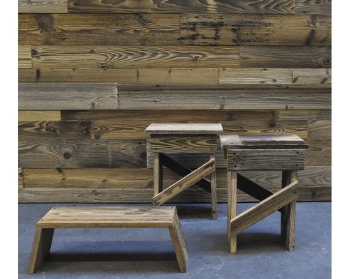 Trois tabourets en bois devant un mur en bois.