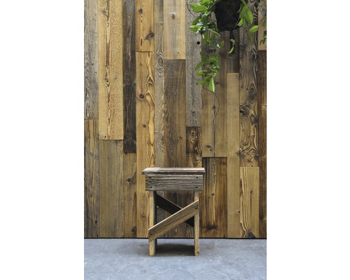 Tabouret en bois devant un mur de panneaux de bois de récupération avec une plante suspendue