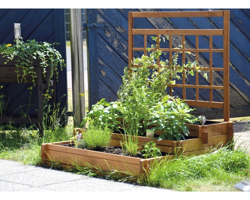 Jardinière surélevée en bois avec treillis et plantations dans le jardin.