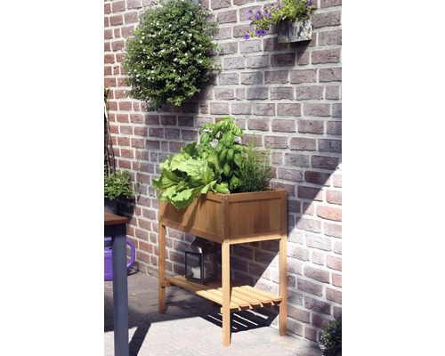 Jardinière sur pieds en bois avec plantes et espace de rangement devant un mur en briques