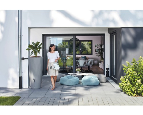 Szene mit Regenwassertank, Pflanze, Frau mit Gießkanne, Sitzsäcken und Terrasse