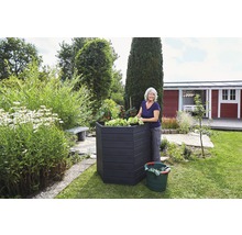 Frau bei der Gartenarbeit an einem Hochbeet im Garten.