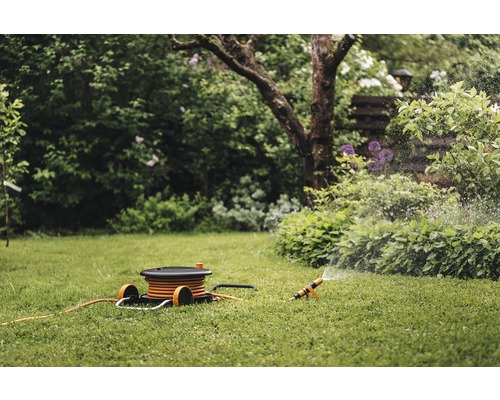 Gartenszene mit Rasensprenger und Schlauchwagen auf einem Rasen