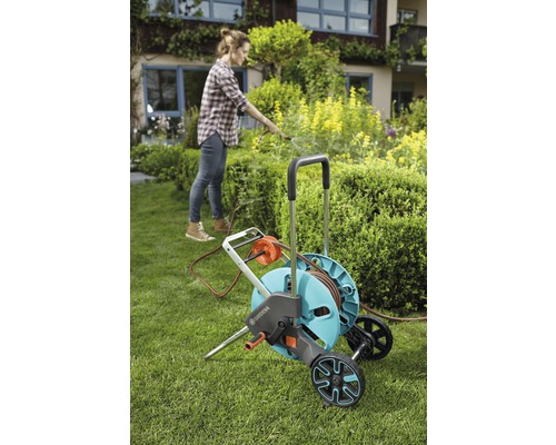 Femme utilisant un chariot de tuyau d''arrosage Gardena dans le jardin