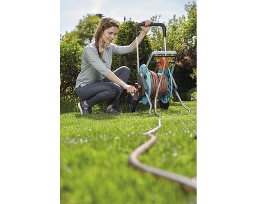 Femme utilise un dévidoir dans le jardin avec un tuyau d''arrosage