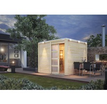 Vue extérieure d''un sauna de jardin en bois avec porte coulissante et éclairage à côté d''une terrasse avec table et barbecue.