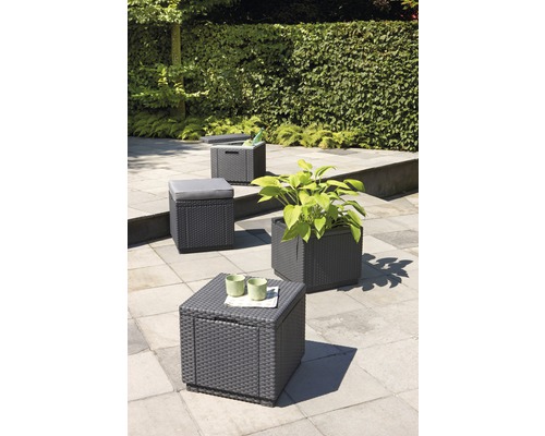 Gartenszene mit Aufbewahrungsboxen in Rattanoptik, die als Tisch, Hocker oder Pflanzgefäß dienen können.
