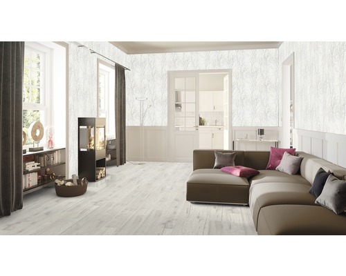 Salon avec canapé, cheminée et papier peint à motif végétal.