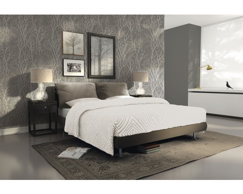 Schlafzimmer mit Doppelbett, Nachttisch, Lampen, Bildern und gemusterter Tapete