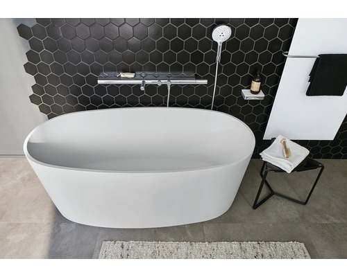 Salle de bain avec baignoire îlot, robinetterie de douche et carreaux muraux hexagonaux.