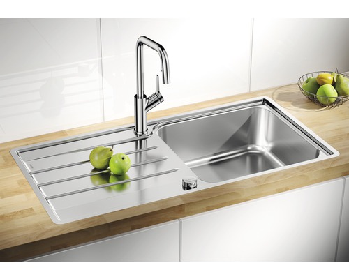 Évier en acier inoxydable avec égouttoir et robinet sur un plan de travail