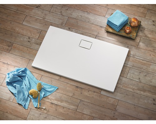 Rechteckige, weisse Duschwanne mit Ablaufgarnitur auf Holzboden