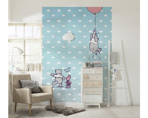 Chambre d''enfant avec papier peint Winnie l''ourson, fauteuil et commode pour une ambiance conviviale.