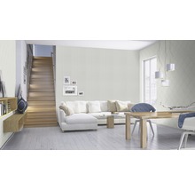 Espace de vie lumineux avec escalier, canapé, table à manger et papier peint à motifs