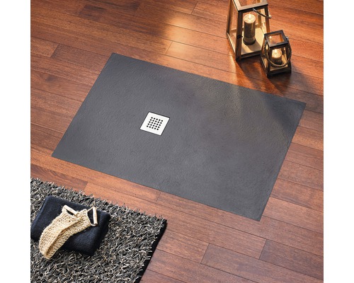 Rechteckige Duschwanne mit Abfluss in einem Badezimmer mit Handtuch und Dekoration