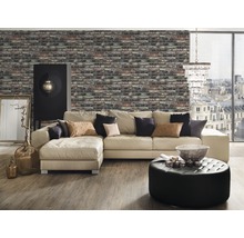 Wohnzimmer mit Ziegelwandtapete, Ecksofa, Ottomanen, Schrank und dekorativen Elementen für ein gemütliches Ambiente.