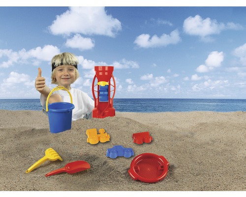 Garçon avec jouets de sable sur la plage, comprenant seau, pelle, râteau, tamis et moulin à sable