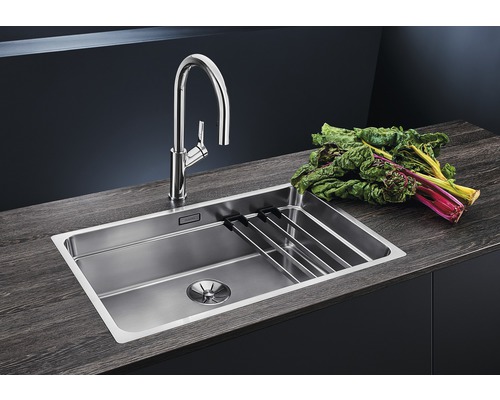 Évier en acier inoxydable avec égouttoir et robinet sur un plan de travail