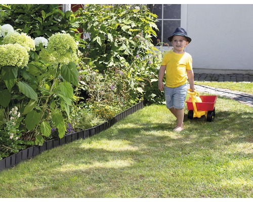 Szene im Garten mit Rasenkante und einem Kind, das einen Wagen zieht