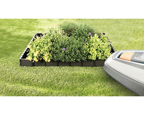 Beeteinfassung aus Kunststoff mit Pflanzen und Rasenmähroboter im Garten.
