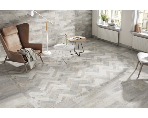 Salon lumineux avec carrelage à chevrons, fauteuil et lampadaire