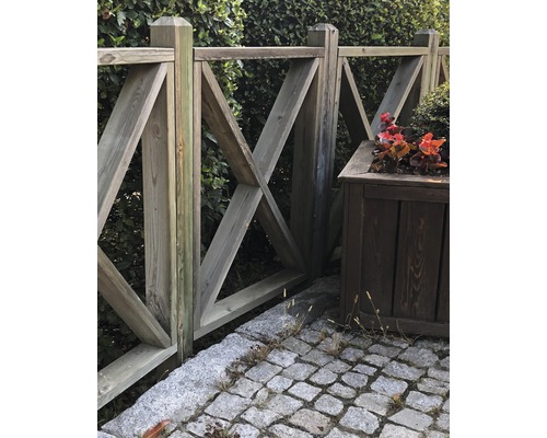 Clôture en bois avec motif décoratif en forme de X et jardinière dans le jardin