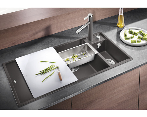 Évier de cuisine avec planche à découper, égouttoir et robinet sur un plan de travail.