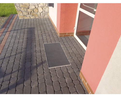 Cour pavée avec rigole de drainage devant un bâtiment