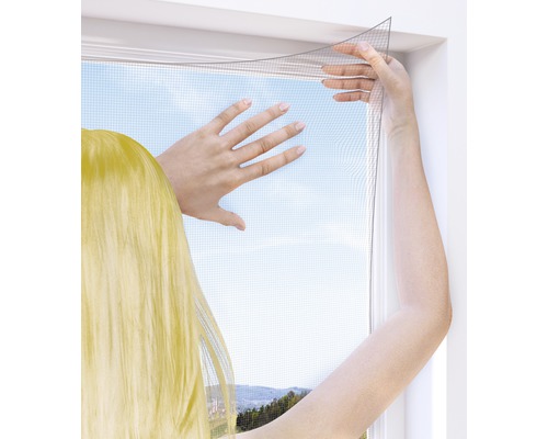 Person befestigt ein Insektenschutzgitter an einem Fenster
