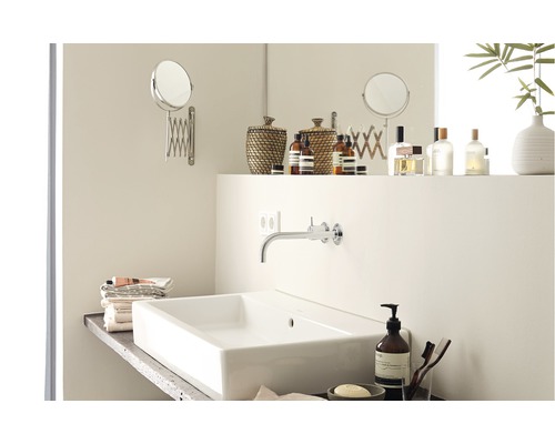 Modernes Badezimmer mit Aufsatzwaschbecken, Wandarmatur, Kosmetikspiegel und Pflegeprodukten