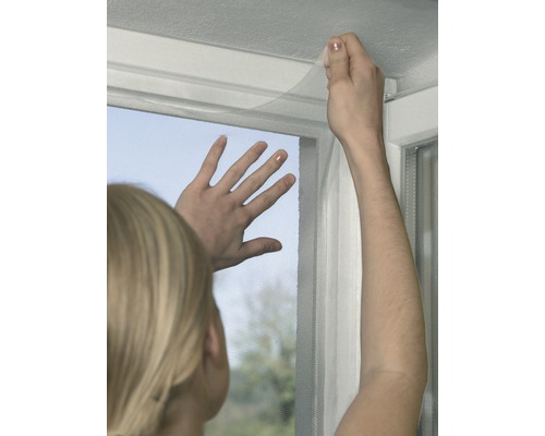 Person befestigt ein Insektenschutzgitter an einem Fenster