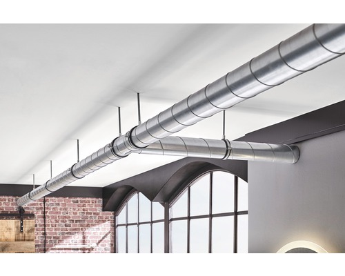 Tuyaux de ventilation métalliques installés dans une pièce avec un mur en briques et de grandes fenêtres.