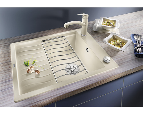 Spüle mit Abtropffläche, Armatur und Geschirr auf einer Küchentheke.