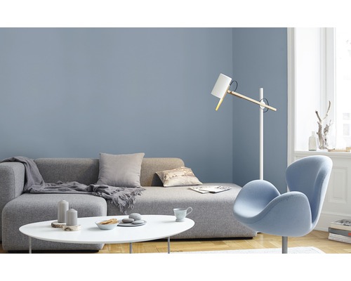 Salon avec canapé gris, table blanche et fauteuil bleu devant un mur bleu